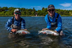 Two anglers hold up rainbow trout.