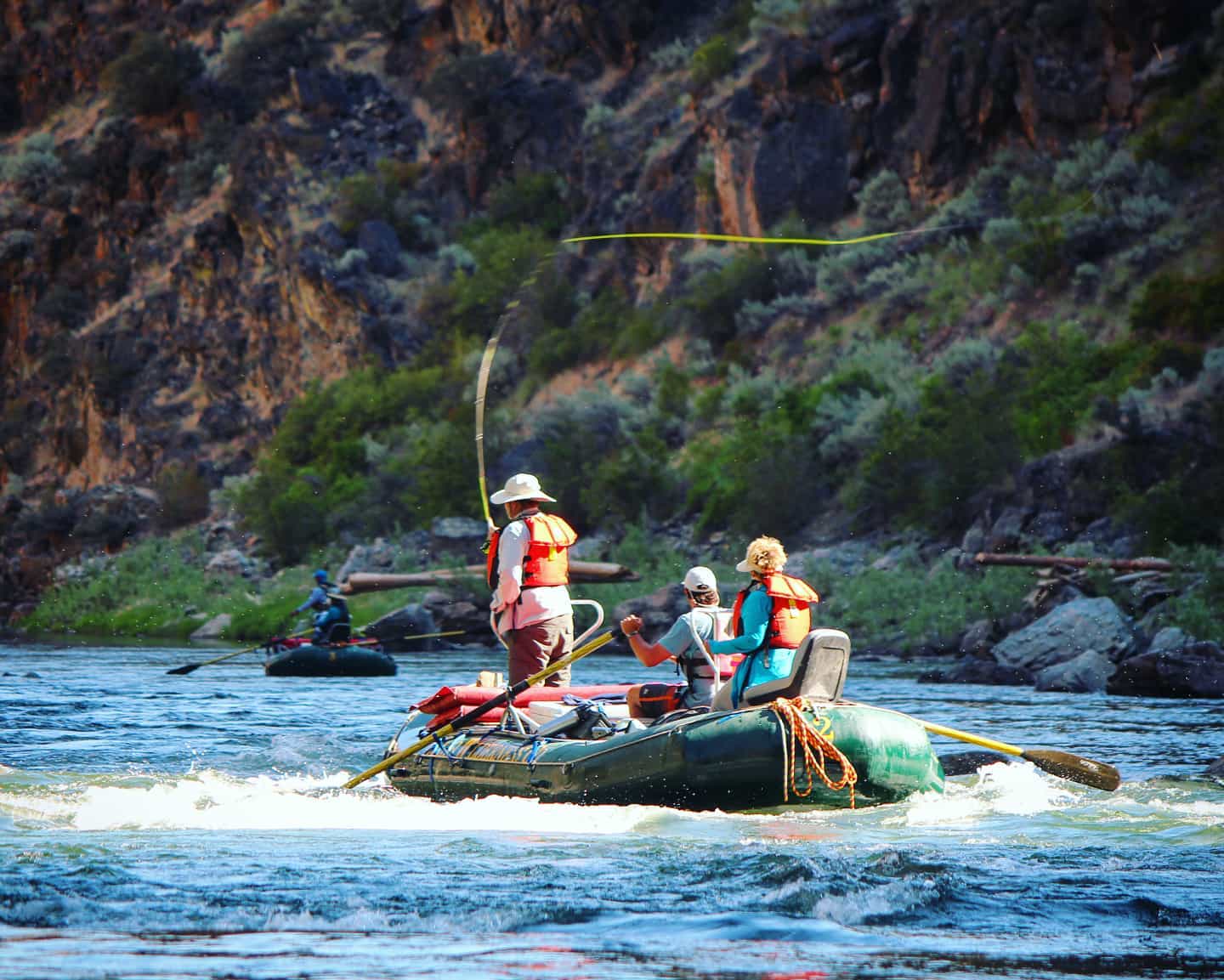 A fly fisherman casts into the Middle Fork of the Salmon River from atop a raft.