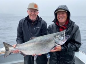 Two men hold up a sizable King Salmon while fishing in British Columbia.