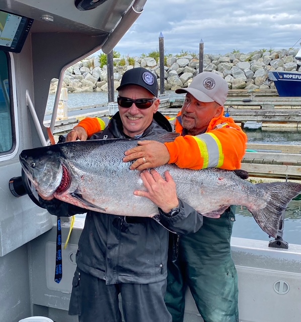 Two fisherman grin as they show off a King Salmon.