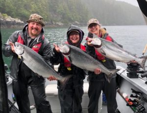 Three happy fisherman hold up King Salmon that they caught in British Columbia.
